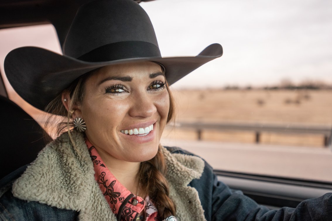 The smiling face of a beautiful cowgirl in her pickup truck